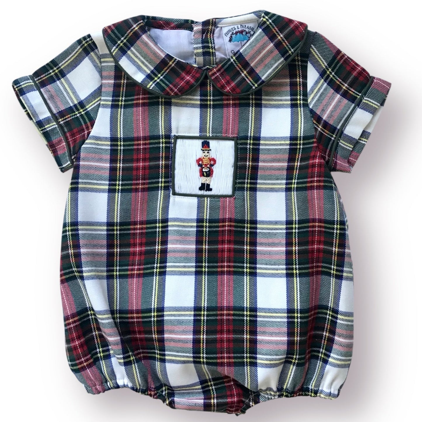 Christmas plaid baby romper with a small patch featuring a smocked drummer boy on a white background