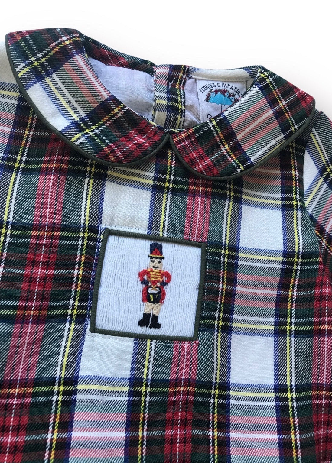 Plaid bubble with embroidered label featuring a nutcracker design.
