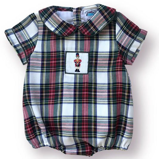 Christmas plaid baby romper with a small patch featuring a smocked drummer boy on a white background