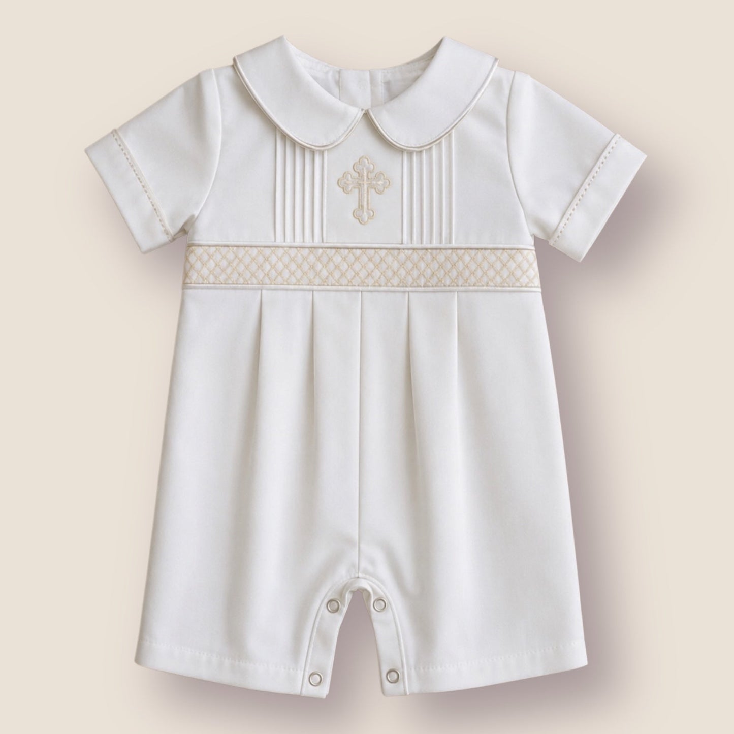 A baby boy's short-sleeved white romper with a Peter Pan collar, featuring a decorative beige-patterned band across the chest with a small embroidered cross, set against a solid beige background.