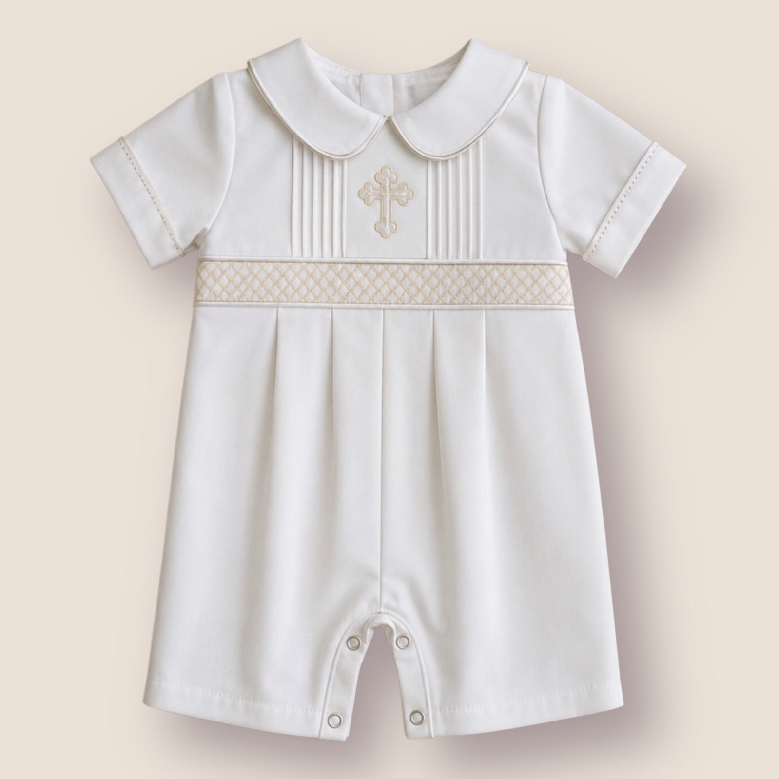 A baby boy's short-sleeved white romper with a Peter Pan collar, featuring a decorative beige-patterned band across the chest with a small embroidered cross, set against a solid beige background.
